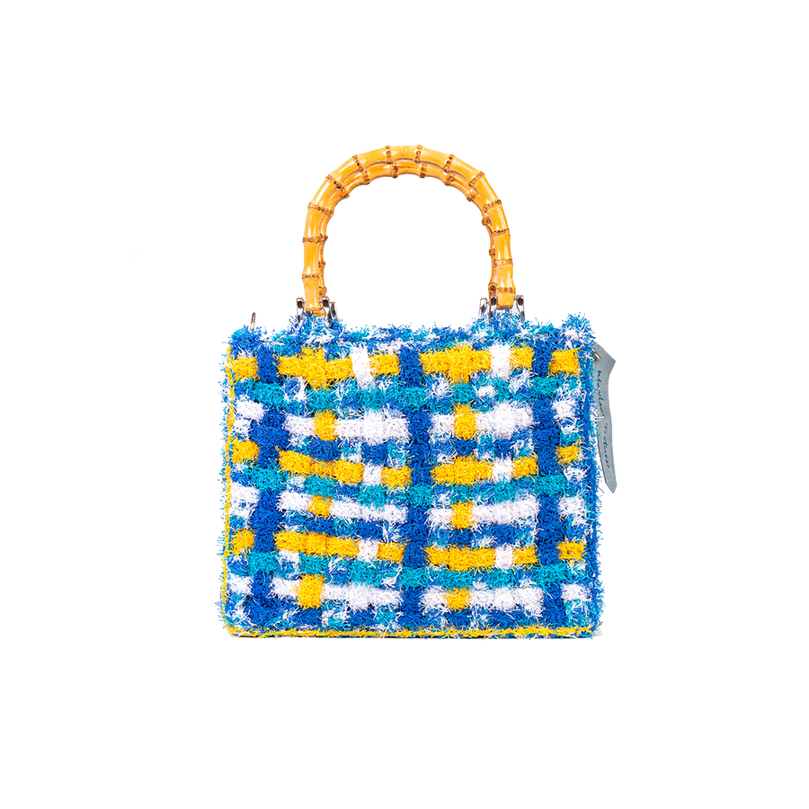 Dai vivaci colori, Tote bag lavorata ad uncinetto con filati provenienti da una merceria nei pressi di S. Buchanan St, Texas, Stati Uniti. I manici in bambù, uno dei simboli identificativi del brand, permettono di indossarla come borsa a mano; La sua tracolla rimovibile, invece,  permette di portare la borsa a spalla. Di manifattura artigianale, prodotta in Italia. 
