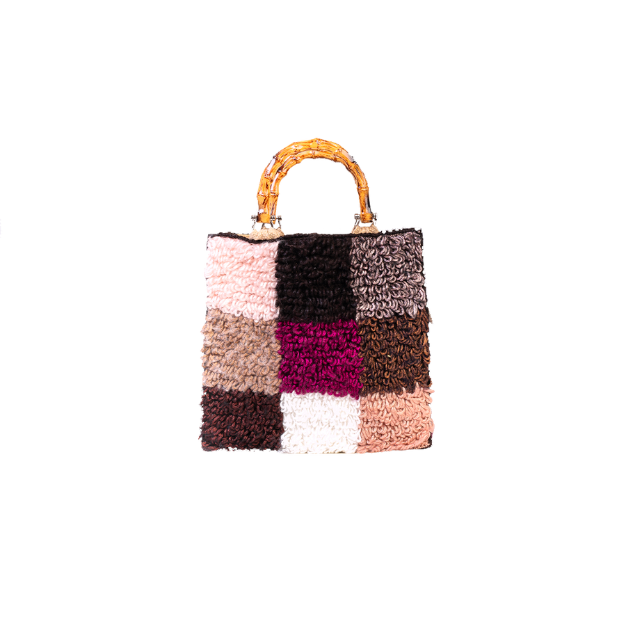Morbida e dai colori che richiamano l'autunno, filo dopo filo, si compone in nove quadratoni una Tote bag unica nel suo genere. I manici in bambù, uno dei simboli identificativi del brand, permettono di indossarla come borsa a mano; La sua tracolla rimovibile, invece, permette di portare la borsa a spalla. Di manifattura artigianale, prodotta in Italia.