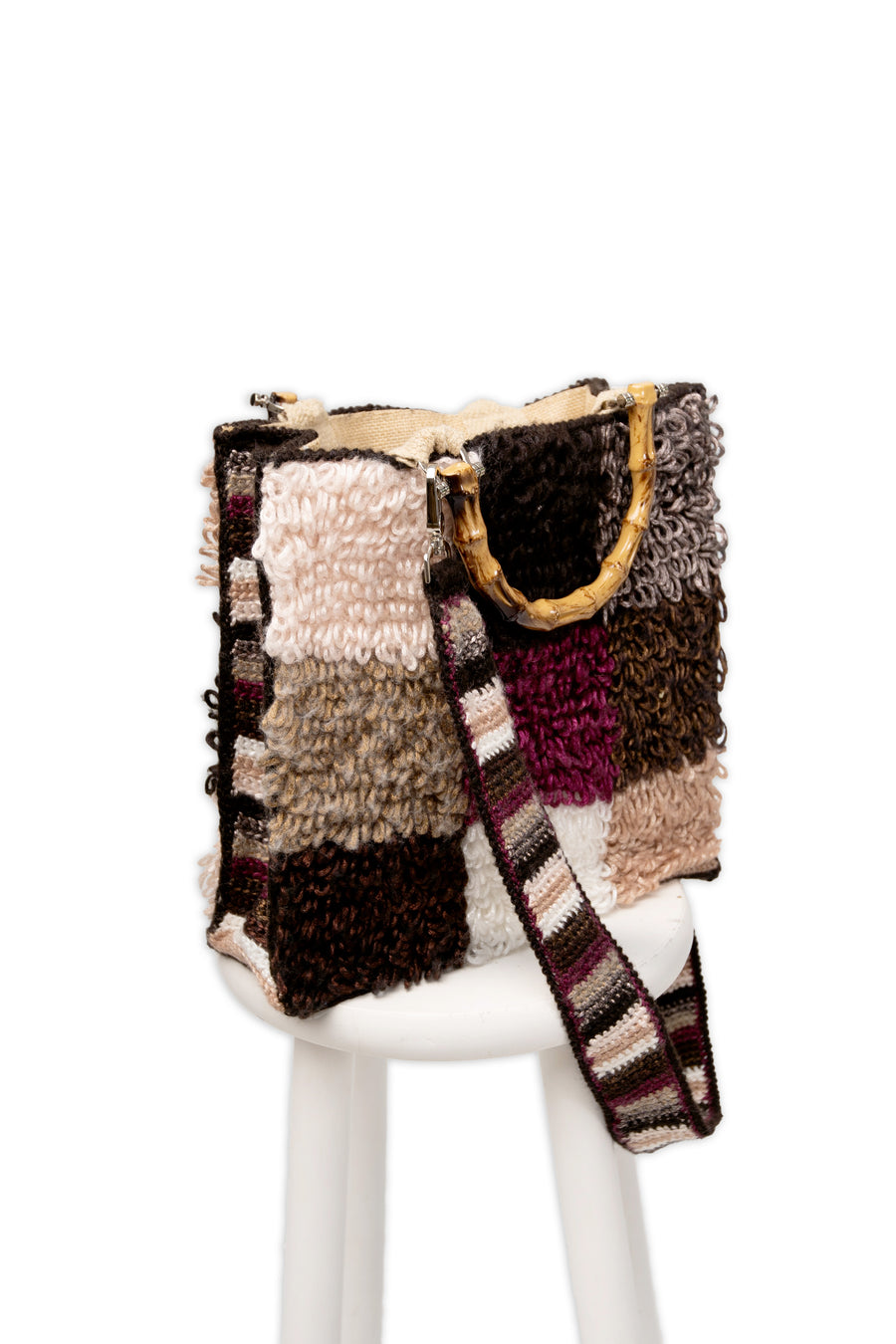 Morbida e dai colori che richiamano l'autunno, filo dopo filo, si compone in nove quadratoni una Tote bag unica nel suo genere. I manici in bambù, uno dei simboli identificativi del brand, permettono di indossarla come borsa a mano; La sua tracolla rimovibile, invece, permette di portare la borsa a spalla. Di manifattura artigianale, prodotta in Italia.