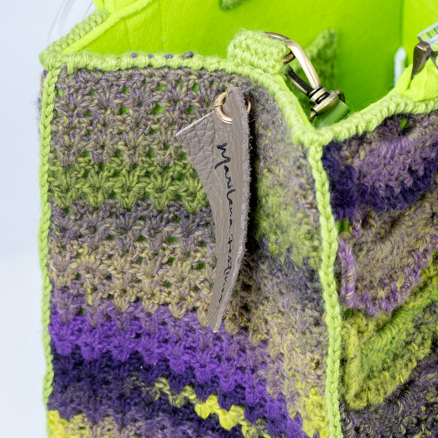 Tote bag di grandi dimensioni realizzata ad uncinetto con pura lana. Impossibile non notarla, ogni mezza luna delle sei righe presenti, dona fascino ed eleganza ad una borsa di assoluta e pregevole fattura. I manici in plexiglass permettono di indossarla come borsa a mano; la sua tracolla in vera pelle, invece, permette di portarla a spalla. Di manifattura artigianale, prodotta in Italia.