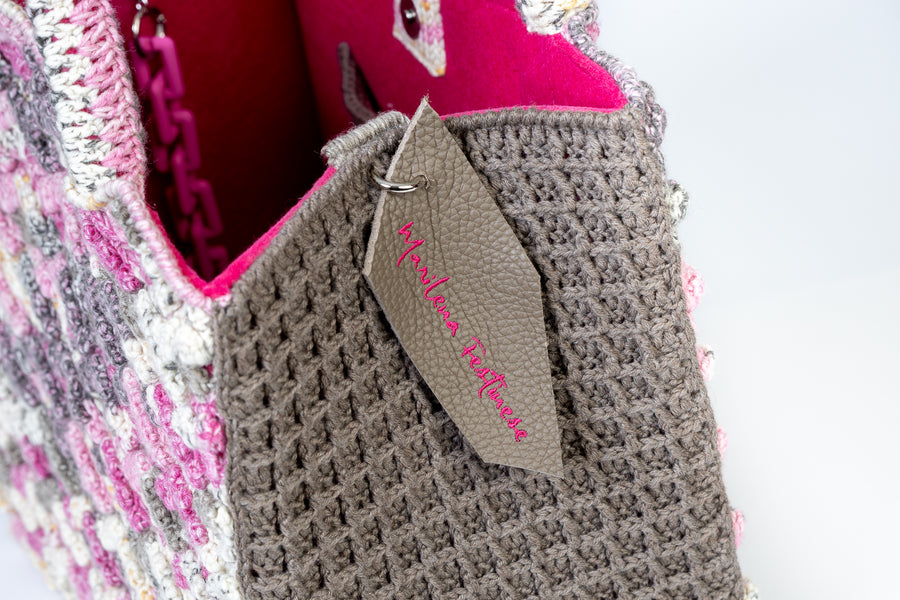 La sovrapposizione di ventagli che si espandono sui due volti ricordano a chi la guarda, un giardino giapponese dai fiori di diverse tonalità di rosa. Shopping Bag invernale è realizzata in pura lana, con manici morbidi rivestiti a mano per portare la borsa a mano ed una tracolla rimovibile per indossarla a spalla. Manifattura artigianale, prodotta in Italia. 