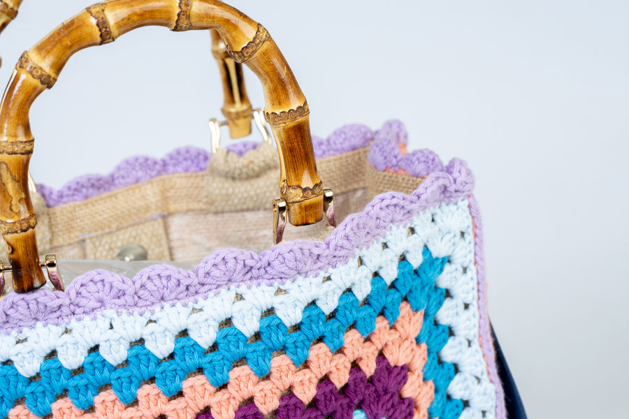 Concentricamente quadrati, due volti di una stessa medaglia con colori contrapposti, compongono queta tote bag di pregevole fattura. I manici in bambù, uno dei simboli identificativi del brand, permettono di indossarla come borsa a mano; Di manifattura artigianale, prodotta in Italia.