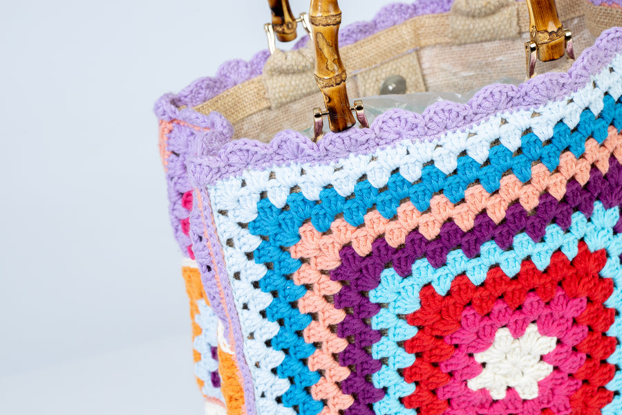 Concentricamente quadrati, due volti di una stessa medaglia con colori contrapposti, compongono queta tote bag di pregevole fattura. I manici in bambù, uno dei simboli identificativi del brand, permettono di indossarla come borsa a mano; Di manifattura artigianale, prodotta in Italia.