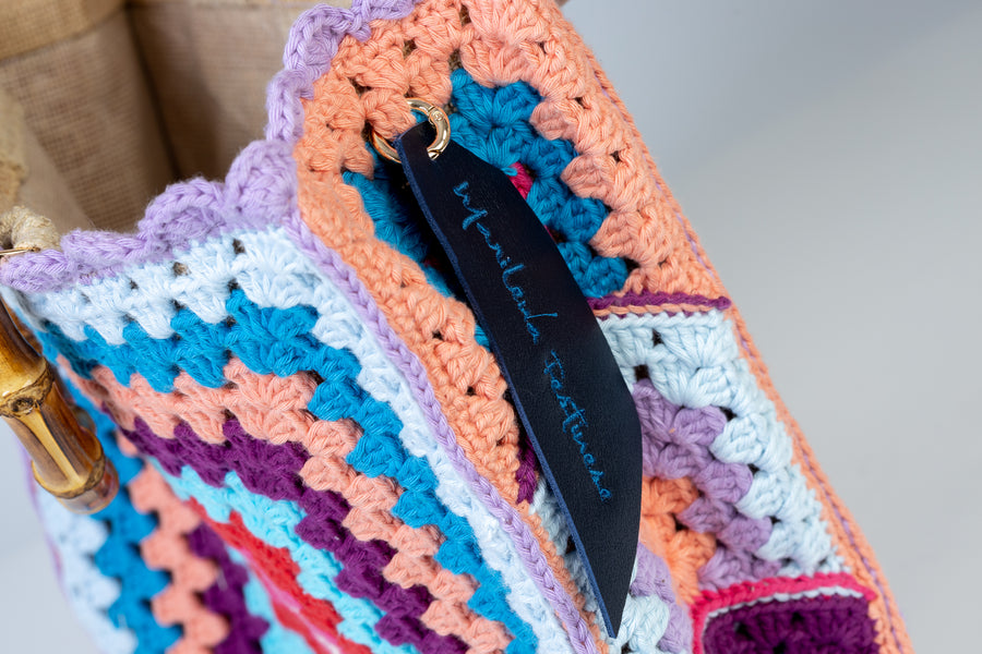 Concentricamente quadrati, due volti di una stessa medaglia con colori contrapposti, compongono queta tote bag di pregevole fattura. I manici in bambù, uno dei simboli identificativi del brand, permettono di indossarla come borsa a mano; Di manifattura artigianale, prodotta in Italia.