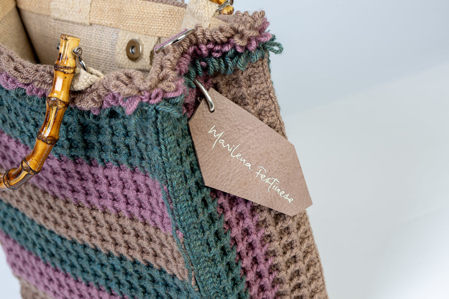 Tote bag lavorata ad uncinetto con la tecnica del punto waffle, composta da sei linee dai colori tenui e delicati. I manici in bambù, uno dei simboli identificativi del brand, permettono di indossarla come borsa a mano; La sua tracolla rimovibile, invece, permette di portare la borsa a spalla. Di manifattura artigianale, prodotta in Italia.