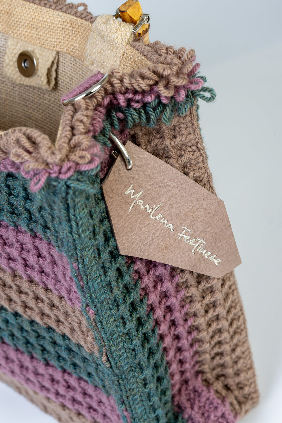 Tote bag lavorata ad uncinetto con la tecnica del punto waffle, composta da sei linee dai colori tenui e delicati. I manici in bambù, uno dei simboli identificativi del brand, permettono di indossarla come borsa a mano; La sua tracolla rimovibile, invece, permette di portare la borsa a spalla. Di manifattura artigianale, prodotta in Italia.