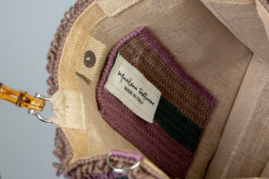 Tote bag lavorata ad uncinetto con la tecnica del punto waffle, composta da sei linee dai colori tenui e delicati. I manici in bambù, uno dei simboli identificativi del brand, permettono di indossarla come borsa a mano; La sua tracolla rimovibile, invece, permette di portare la borsa a spalla. Di manifattura artigianale, prodotta in Italia.