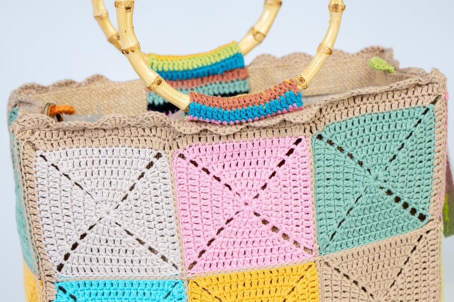 Design patchwork, Tote Bag di medie dimensioni, realizzata all’uncinetto. Estiva ed eccentrica questo pezzo è unico, composto da grandi quadratoni uniti grazie ad intrecci. I manici in bambù, uno dei simboli identificativi del brand, permettono di indossarla come borsa a mano; La sua tracolla rimovibile, invece, permette di portare la borsa a spalla. Di manifattura artigianale, prodotta in Italia.