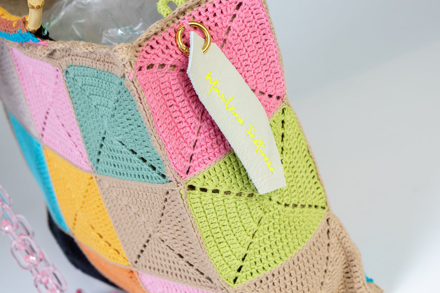Design patchwork, Tote Bag di medie dimensioni, realizzata all’uncinetto. Estiva ed eccentrica questo pezzo è unico, composto da grandi quadratoni uniti grazie ad intrecci. I manici in bambù, uno dei simboli identificativi del brand, permettono di indossarla come borsa a mano; La sua tracolla rimovibile, invece, permette di portare la borsa a spalla. Di manifattura artigianale, prodotta in Italia.