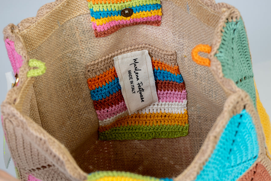 Design patchwork, Tote Bag di medie dimensioni, realizzata all’uncinetto. Estiva ed eccentrica questo pezzo è unico, composto da grandi quadratoni uniti grazie ad intrecci. I manici in bambù, uno dei simboli identificativi del brand, permettono di indossarla come borsa a mano; La sua tracolla rimovibile, invece, permette di portare la borsa a spalla. Di manifattura artigianale, prodotta in Italia.