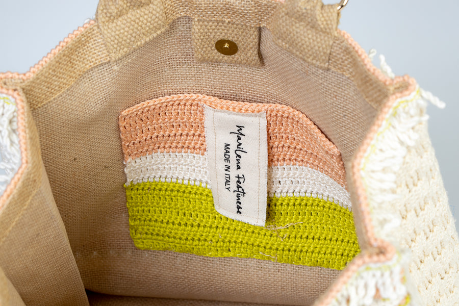 Incantevole Tote Bag composta interamente da ricercati dettagli, utilizzando il "Punto Tulipano". Piccoli fiori di un rosa pallido si alternano a linee di un bianco morbido. I manici in bambù, uno dei simboli identificativi del brand, permettono di indossarla come borsa a mano; La sua tracolla rimovibile, invece, permette di portare la borsa a spalla. Di manifattura artigianale, prodotta in Italia.