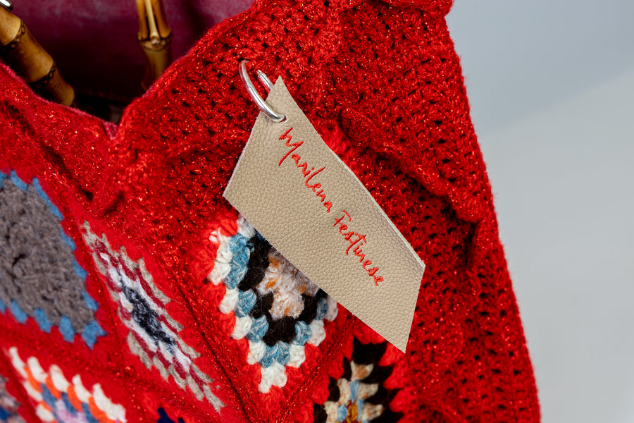 Lavorazione all’uncinetto con mattonelle dal tono rosso accesso, vibranti, gioiose e intense. I manici in bambù, uno dei simboli identificativi del brand, permettono di indossarla come borsa a mano; Due manici più lunghi e rimovibile, invece, permettono di portare la borsa a spalla. Di manifattura artigianale, prodotta in Italia.