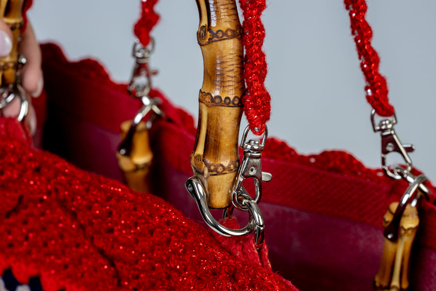 Lavorazione all’uncinetto con mattonelle dal tono rosso accesso, vibranti, gioiose e intense. I manici in bambù, uno dei simboli identificativi del brand, permettono di indossarla come borsa a mano; Due manici più lunghi e rimovibile, invece, permettono di portare la borsa a spalla. Di manifattura artigianale, prodotta in Italia.