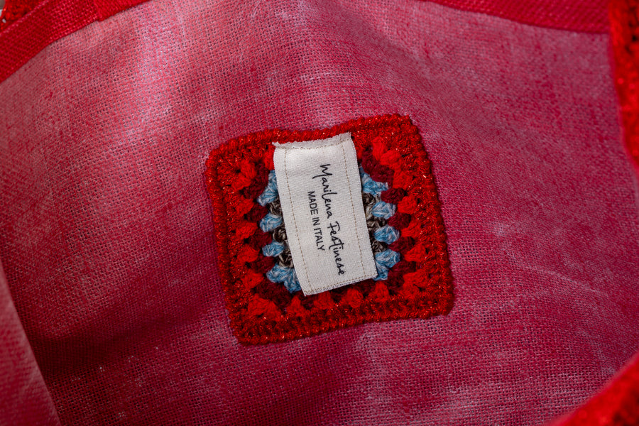 Lavorazione all’uncinetto con mattonelle dal tono rosso accesso, vibranti, gioiose e intense. I manici in bambù, uno dei simboli identificativi del brand, permettono di indossarla come borsa a mano; Due manici più lunghi e rimovibile, invece, permettono di portare la borsa a spalla. Di manifattura artigianale, prodotta in Italia.