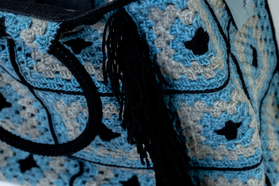 Shopping Bag lavorata mediante uncinetto con motivi originali di un celeste incanto e lunghe frange blu. Dedicata alle acque cristalline del mar mediterraneo. I suoi manici rigidi rivestiti a mano, permettono di indossarla come borsa a mano; La sua tracolla rimovibile, invece, permette di portare la borsa a spalla. Di manifattura artigianale, prodotta in Italia.