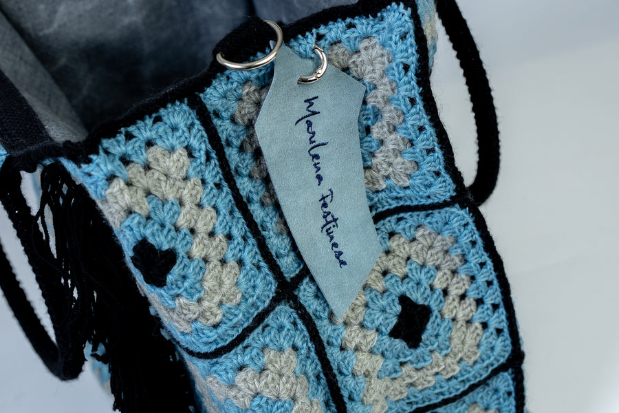 Shopping Bag lavorata mediante uncinetto con motivi originali di un celeste incanto e lunghe frange blu. Dedicata alle acque cristalline del mar mediterraneo. I suoi manici rigidi rivestiti a mano, permettono di indossarla come borsa a mano; La sua tracolla rimovibile, invece, permette di portare la borsa a spalla. Di manifattura artigianale, prodotta in Italia.