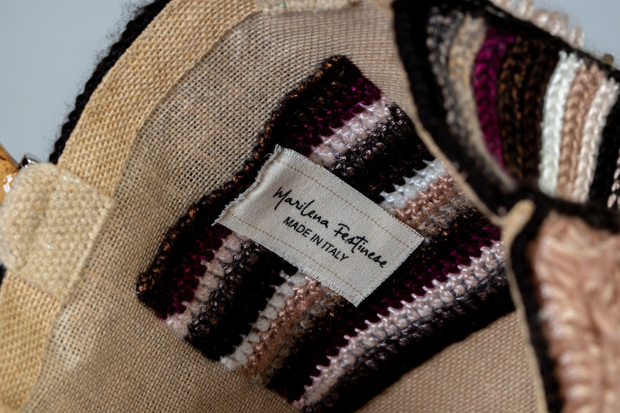 Morbida e dai colori che richiamano l'autunno, filo dopo filo, si compone in nove quadratoni una Tote bag unica nel suo genere. I manici in bambù, uno dei simboli identificativi del brand, permettono di indossarla come borsa a mano; La sua tracolla rimovibile, invece, permette di portare la borsa a spalla. Di manifattura artigianale, prodotta in Italia.