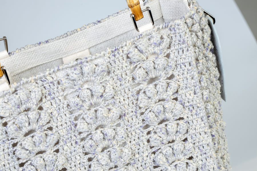 "Concha" simbolo di vita e di rinascita è realizzata ad uncinetto con l’unione di diversi stili, che rendono questa Tote Bag unica nel suo genere. I manici in bambù, uno dei simboli identificativi del brand, permettono di indossarla come borsa a mano; La sua tracolla rimovibile, invece, permette di portare la borsa a spalla. Di manifattura artigianale, prodotta in Italia.