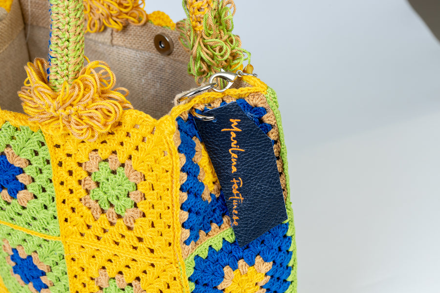 Questa Tote Bag dal design patchwork presenta una palette di colori allegri e vivaci. Realizzata interamente a mano con i suoi più variegati dettagli rappresenta il fascino meticoloso della natura che non si accontenta mai e continua sempre a stupire. I manici in bambù, uno dei simboli identificativi del brand, permettono di indossarla come borsa a mano. Di manifattura artigianale, prodotta in Italia.